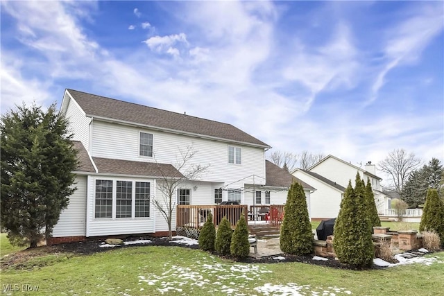 back of property featuring a wooden deck and a yard