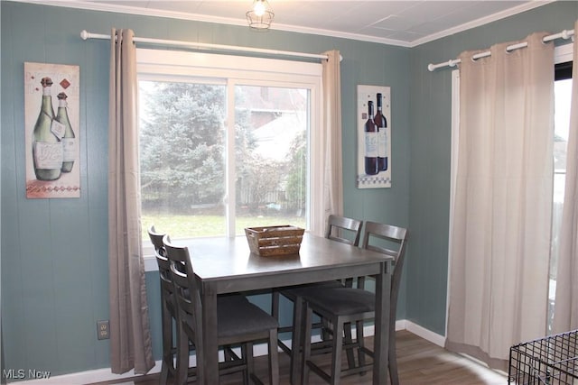 dining room with wood-type flooring, ornamental molding, and a healthy amount of sunlight