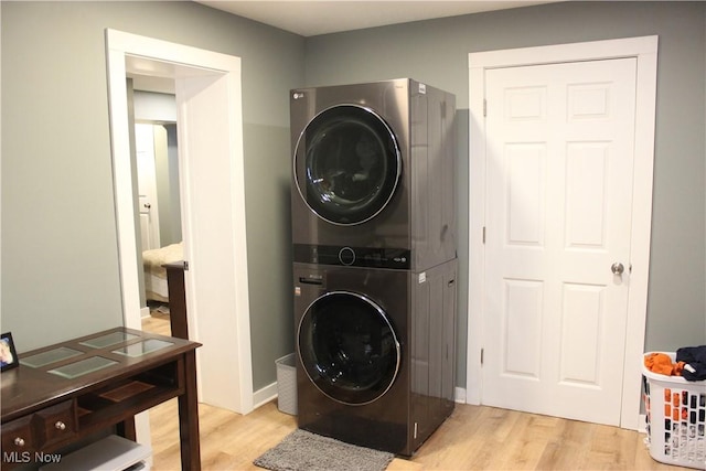 clothes washing area with stacked washer / drying machine and light wood-type flooring