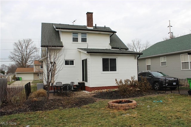 back of house featuring a yard, a patio area, and an outdoor fire pit