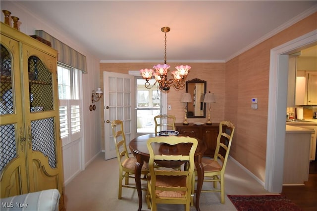 dining room featuring an inviting chandelier, crown molding, and carpet floors