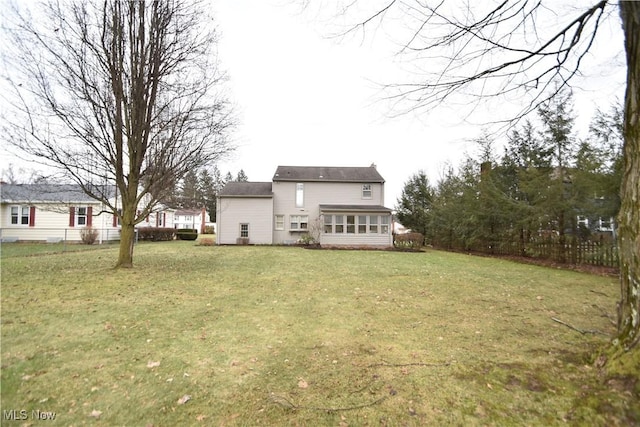 rear view of property featuring a sunroom and a yard