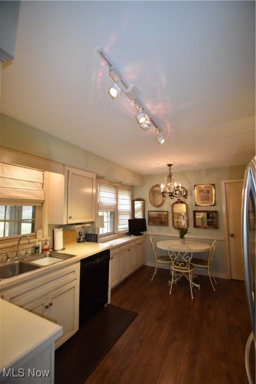 kitchen featuring sink, dark hardwood / wood-style floors, black dishwasher, white cabinets, and decorative light fixtures