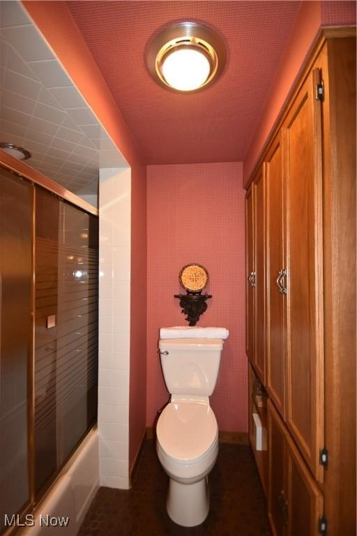 bathroom with enclosed tub / shower combo and toilet