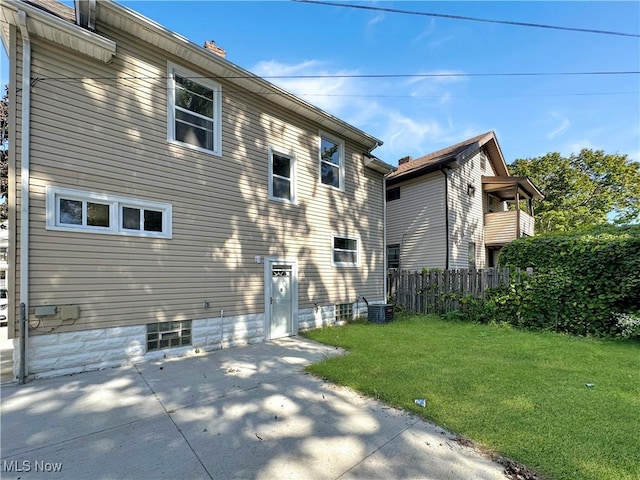 back of house with a patio area, a lawn, and central air condition unit