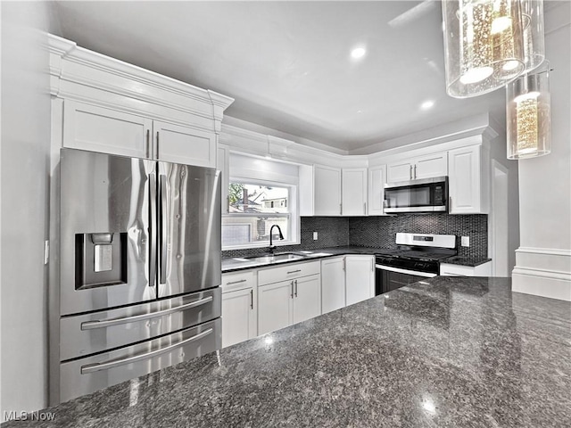 kitchen with appliances with stainless steel finishes, pendant lighting, sink, dark stone countertops, and white cabinets