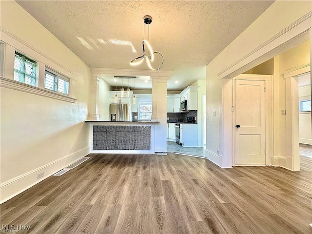 kitchen with white cabinetry, appliances with stainless steel finishes, wood-type flooring, and kitchen peninsula