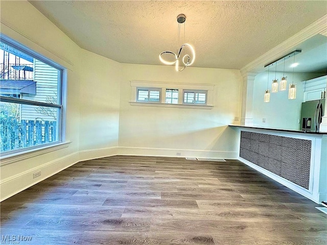 unfurnished dining area featuring a chandelier, hardwood / wood-style floors, and a textured ceiling