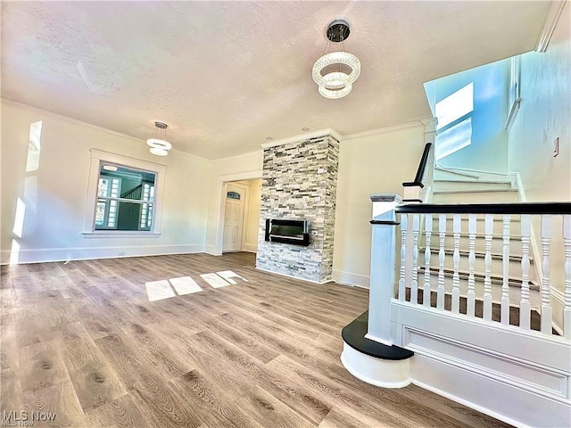 unfurnished living room featuring a stone fireplace, hardwood / wood-style floors, and a textured ceiling