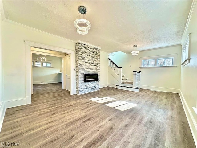 unfurnished living room with crown molding, a fireplace, hardwood / wood-style floors, and a textured ceiling