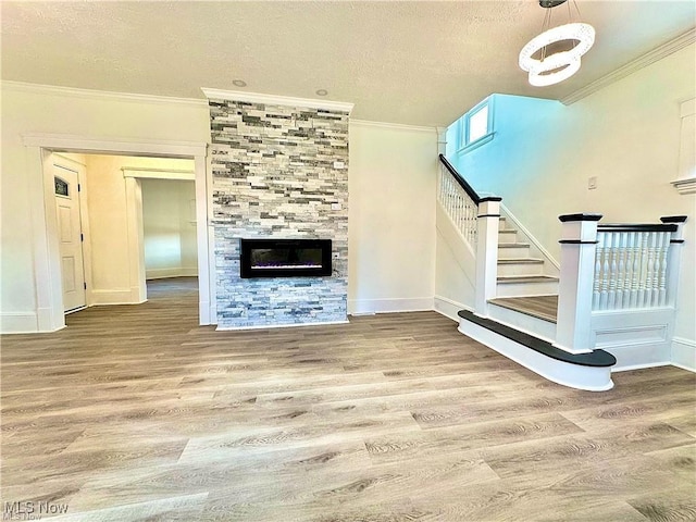 unfurnished living room featuring crown molding, a tile fireplace, a textured ceiling, and hardwood / wood-style flooring