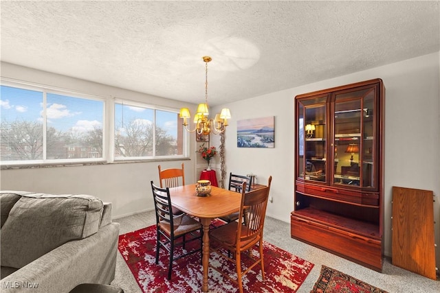 carpeted dining room featuring a chandelier and a textured ceiling