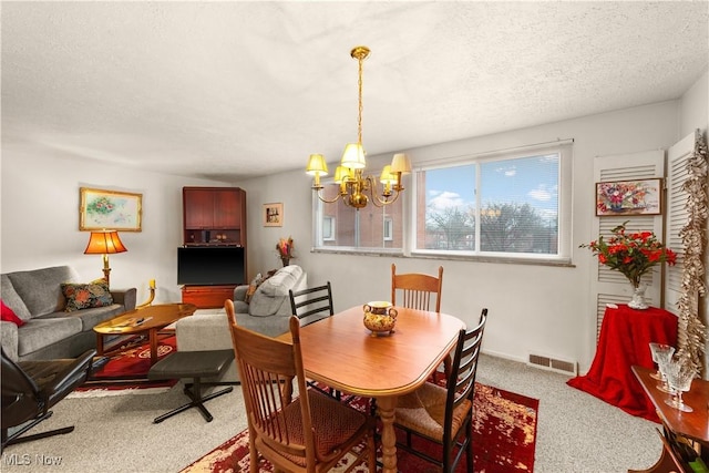 carpeted dining room featuring an inviting chandelier and a textured ceiling