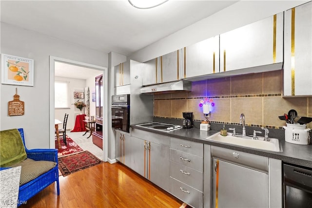 kitchen featuring sink, gray cabinetry, light hardwood / wood-style flooring, decorative backsplash, and black appliances