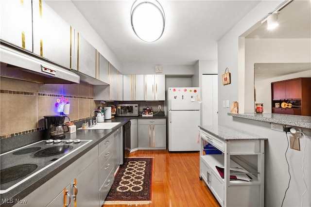 kitchen featuring tasteful backsplash, sink, white fridge, light hardwood / wood-style floors, and cooktop