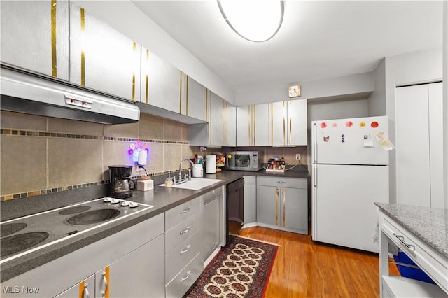 kitchen with cooktop, sink, light hardwood / wood-style flooring, white fridge, and decorative backsplash