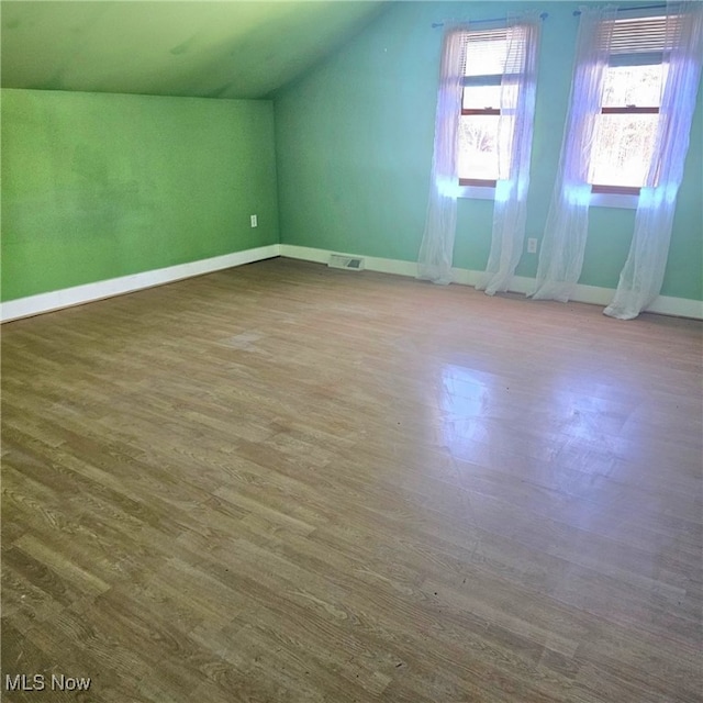 bonus room with visible vents, lofted ceiling, baseboards, and wood finished floors