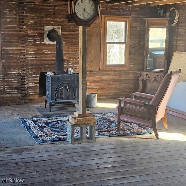 interior space with wooden walls, wood finished floors, and a wood stove