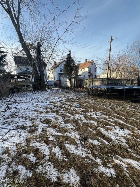 yard layered in snow featuring a trampoline