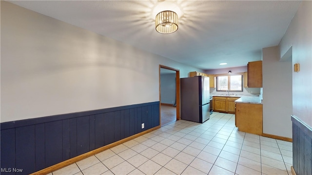 kitchen with stainless steel fridge, sink, and light tile patterned floors