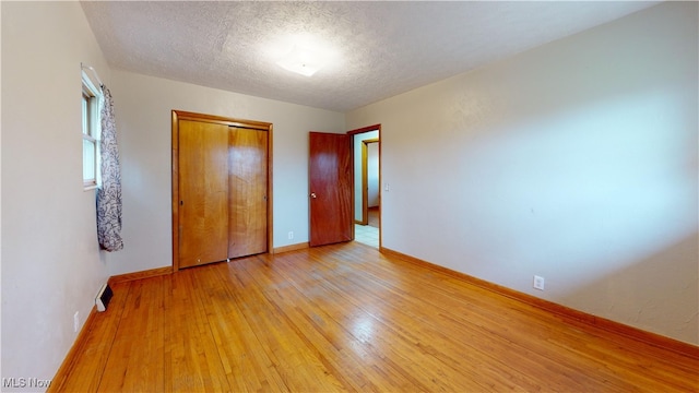 unfurnished bedroom with light hardwood / wood-style flooring, a closet, and a textured ceiling