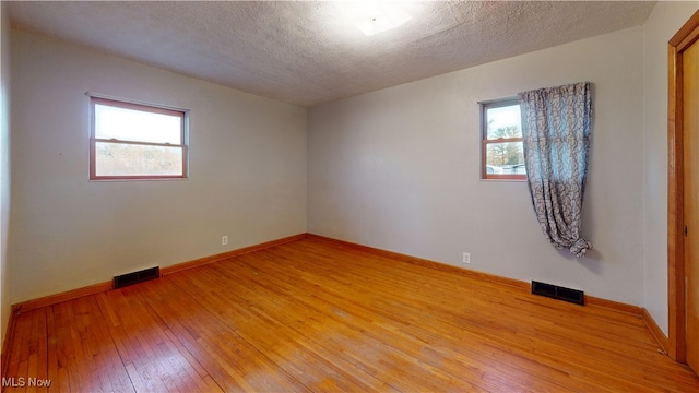 spare room featuring hardwood / wood-style floors and a textured ceiling