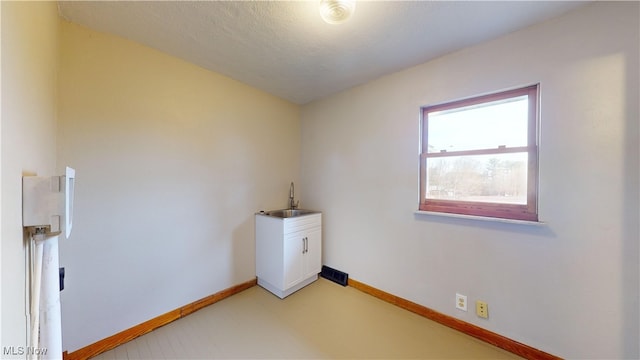 unfurnished room featuring sink and a textured ceiling