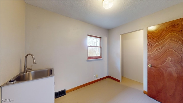 clothes washing area with sink and a textured ceiling