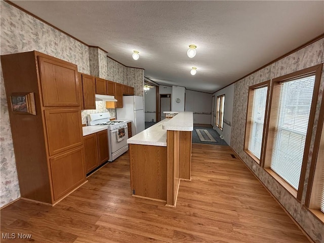 kitchen featuring crown molding, white appliances, a center island, and light hardwood / wood-style floors