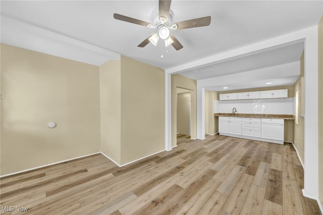 unfurnished living room with sink, ceiling fan, and light hardwood / wood-style flooring