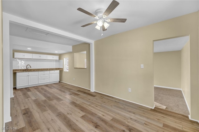 unfurnished living room featuring sink, ceiling fan, and light wood-type flooring