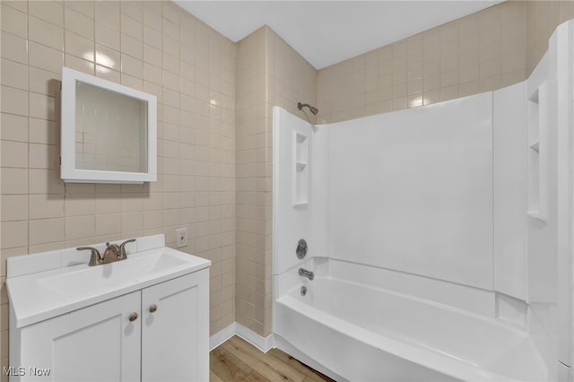 bathroom featuring hardwood / wood-style floors, shower / tub combination, tile walls, and vanity