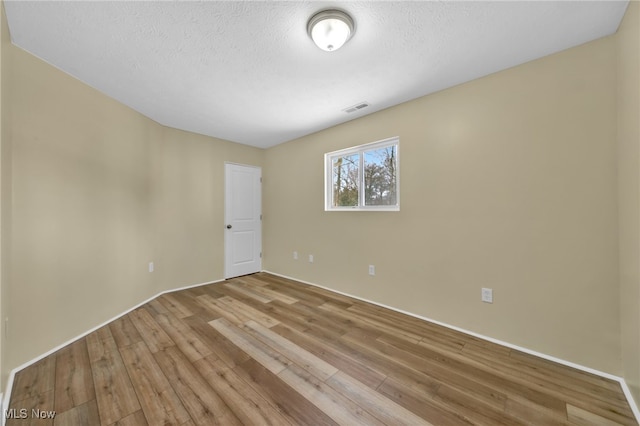 empty room featuring light hardwood / wood-style floors and a textured ceiling