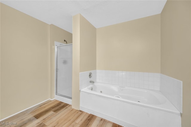 bathroom featuring plus walk in shower, hardwood / wood-style floors, and a textured ceiling