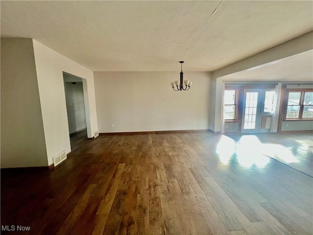 unfurnished dining area featuring dark wood-type flooring and a chandelier