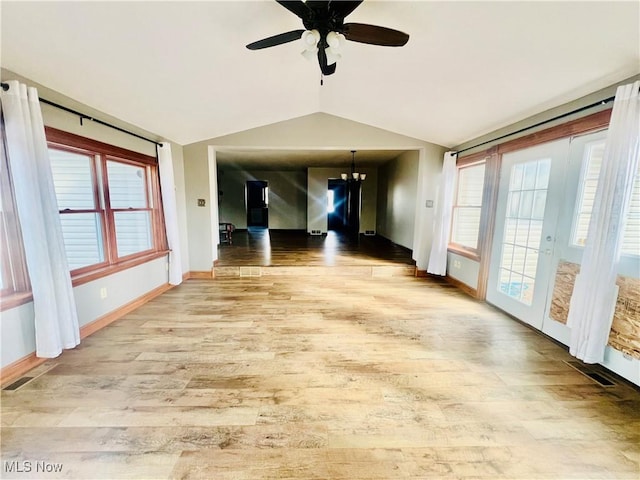 empty room featuring lofted ceiling, ceiling fan with notable chandelier, and wood-type flooring