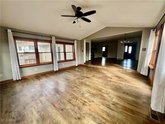 unfurnished living room featuring hardwood / wood-style flooring, ceiling fan with notable chandelier, and vaulted ceiling