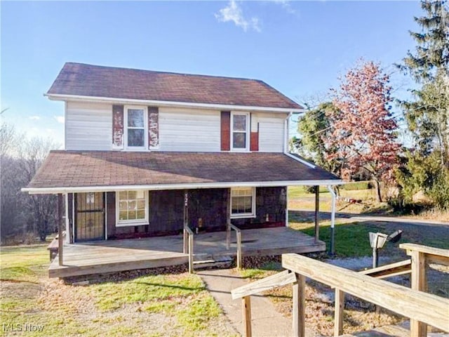 rear view of property featuring a porch and a lawn