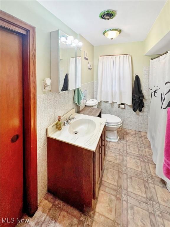 bathroom with vanity, toilet, and tile walls