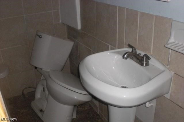 bathroom with toilet and tile walls