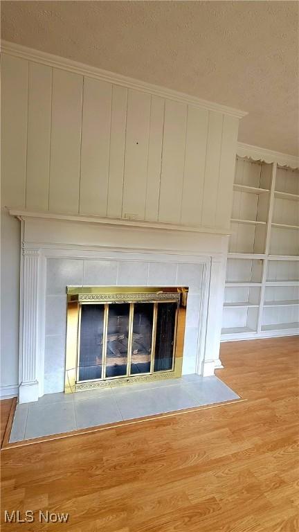 details featuring a tile fireplace, wood-type flooring, built in features, and a textured ceiling