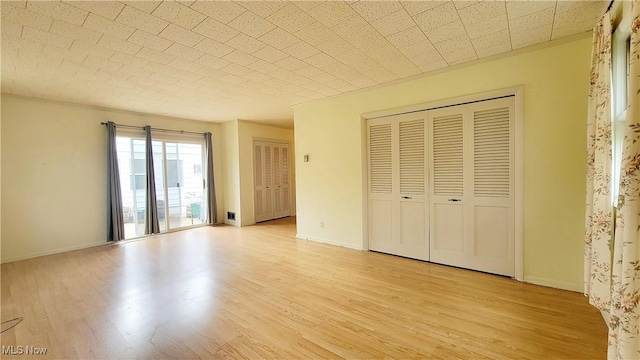 unfurnished bedroom featuring two closets and light wood-type flooring