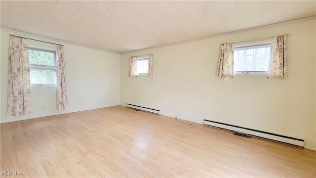 spare room with a baseboard radiator, a textured ceiling, and light hardwood / wood-style floors