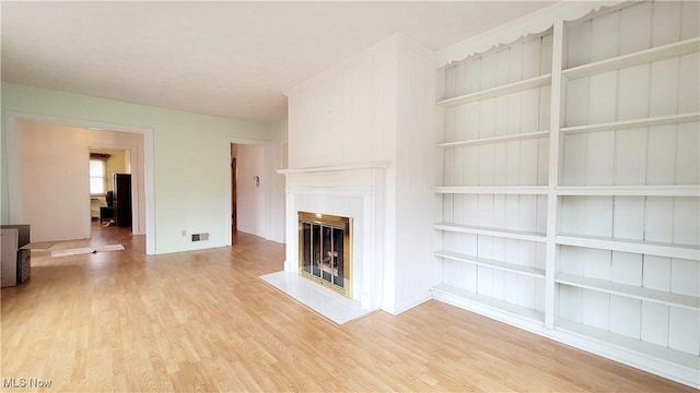 unfurnished living room featuring light hardwood / wood-style floors and built in shelves