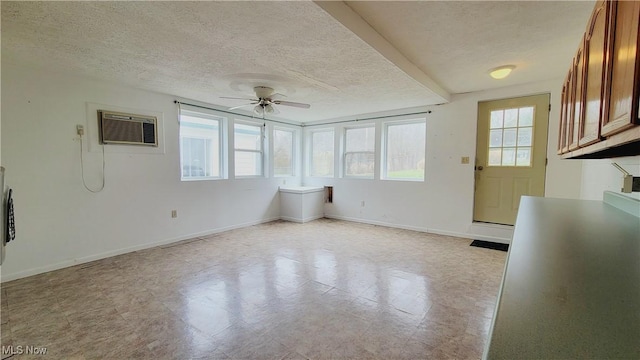 unfurnished living room with ceiling fan, a wall unit AC, and a textured ceiling