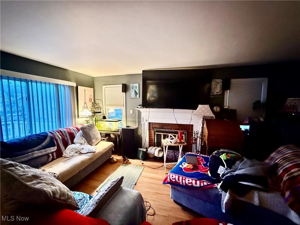 living room featuring a brick fireplace and wood-type flooring