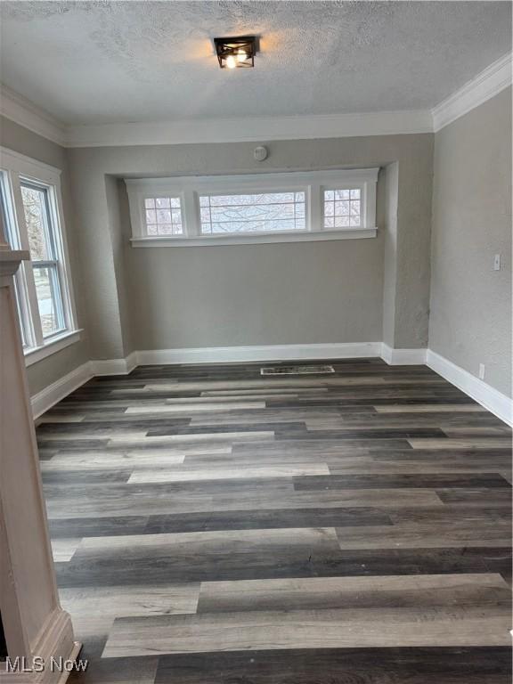 unfurnished room with dark hardwood / wood-style flooring, ornamental molding, and a textured ceiling