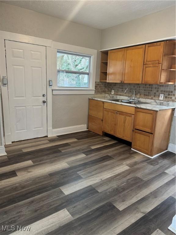 kitchen featuring tasteful backsplash, sink, dark wood-type flooring, and a textured ceiling