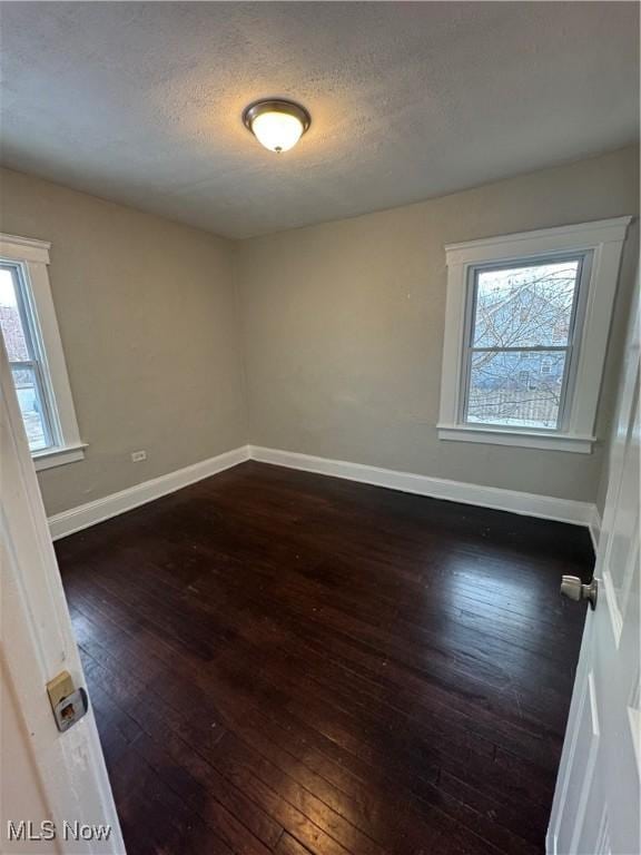 empty room featuring dark wood-type flooring and a textured ceiling