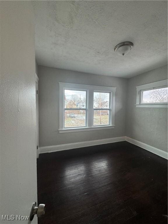 spare room with dark hardwood / wood-style floors and a textured ceiling